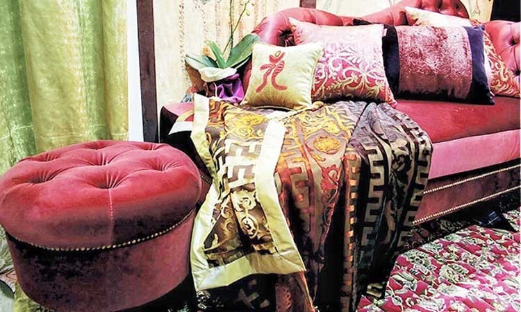 Red sofa and ottoman covered in detailed pillows and blankets